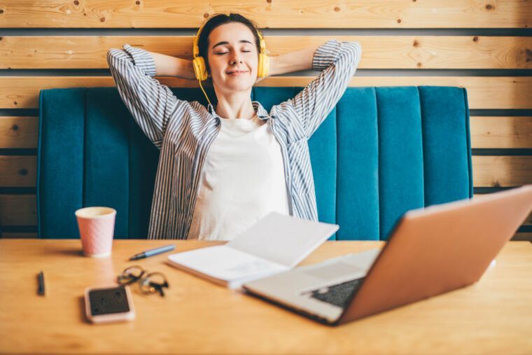Kobieta w słuchawkach robi przerwę przy laptopie w coworkingu